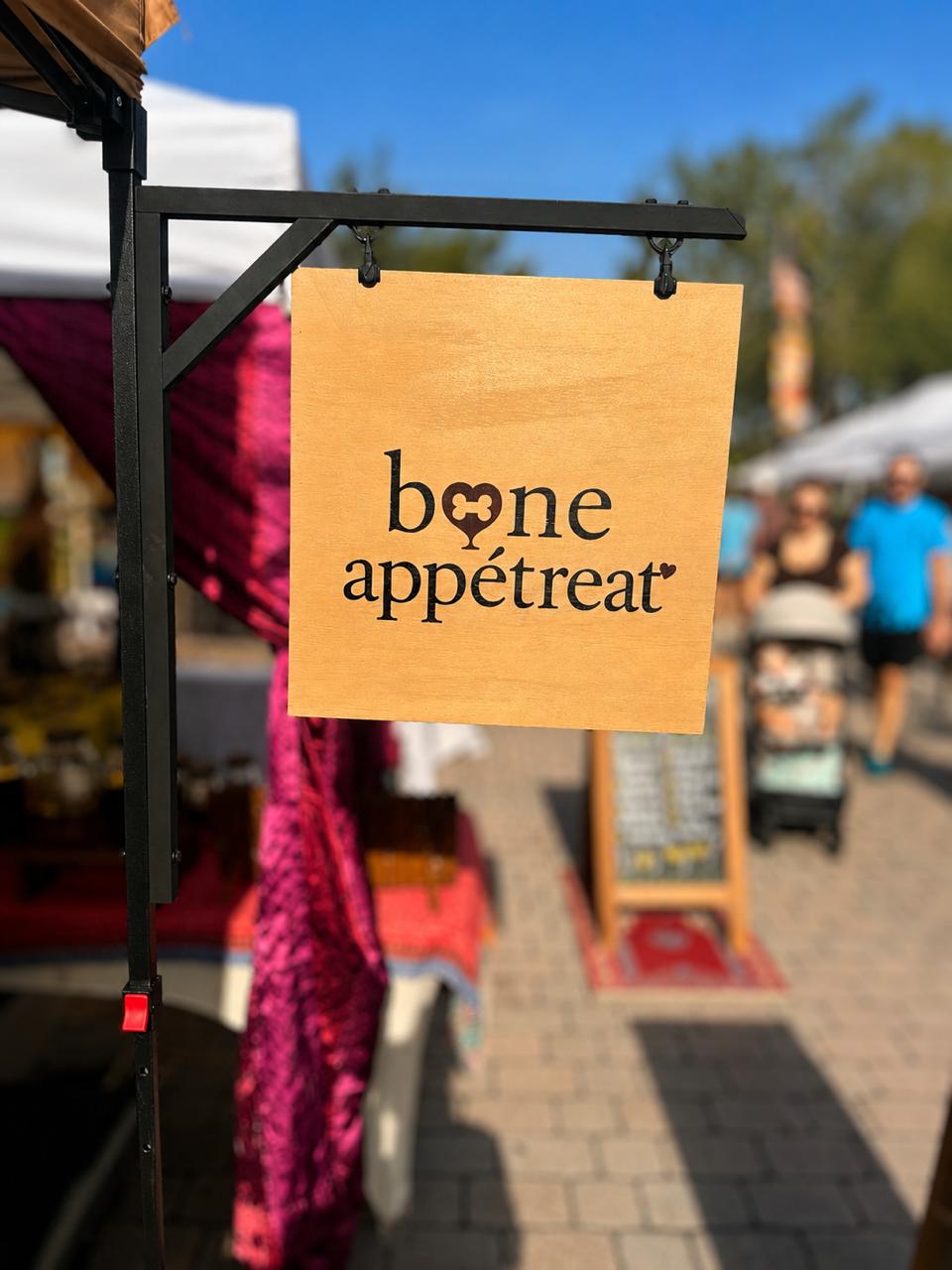 The wooden Bone Appétreat sign hanging at the farmers market booth